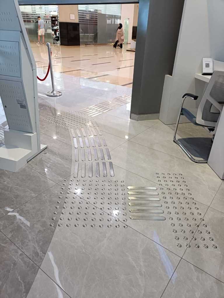 Interior view of the Al Barsha Government Service Center featuring stainless steel tactile studs and directional lines installed on the floor for enhanced accessibility.