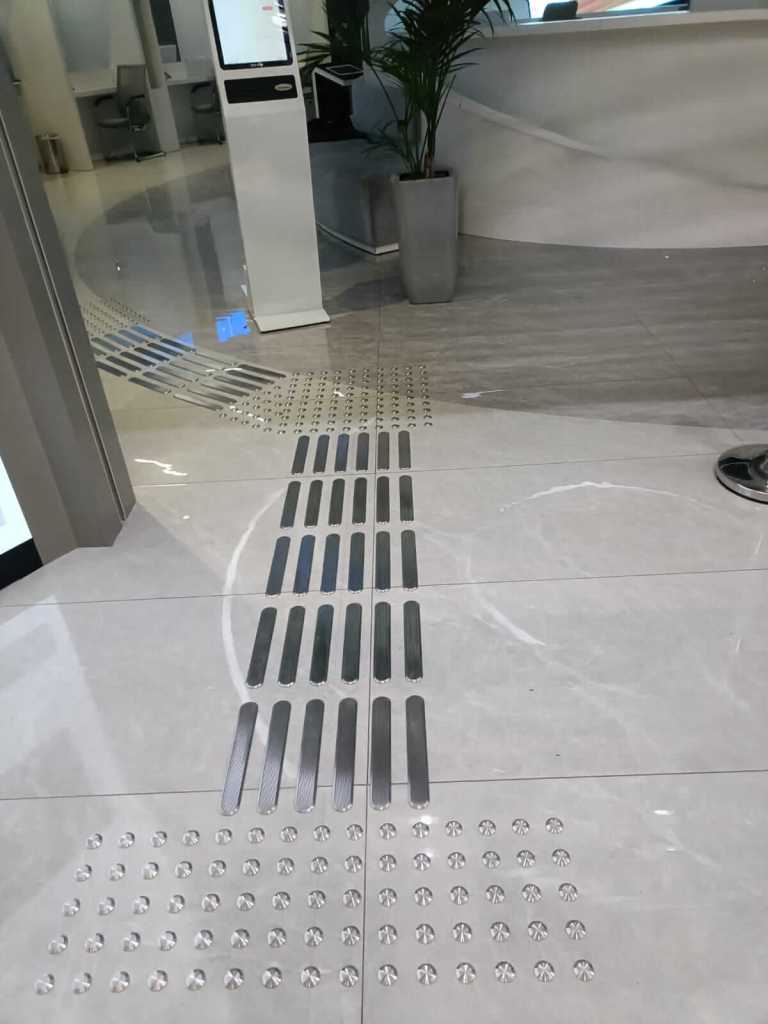 Interior view of the Al Barsha Government Service Center showing stainless steel tactile studs and directional lines on the floor, enhancing accessibility for high-traffic areas.