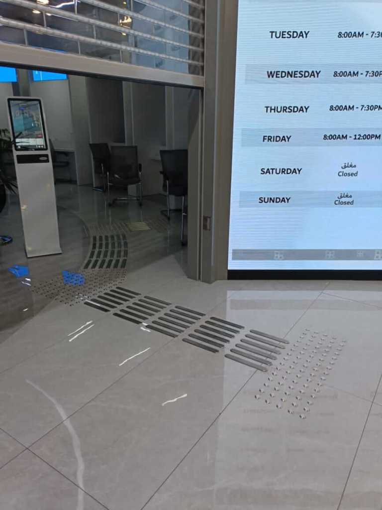 Interior view of the Al Barsha Government Service Center showing installed stainless steel tactile studs and directional lines on the floor for enhanced accessibility.