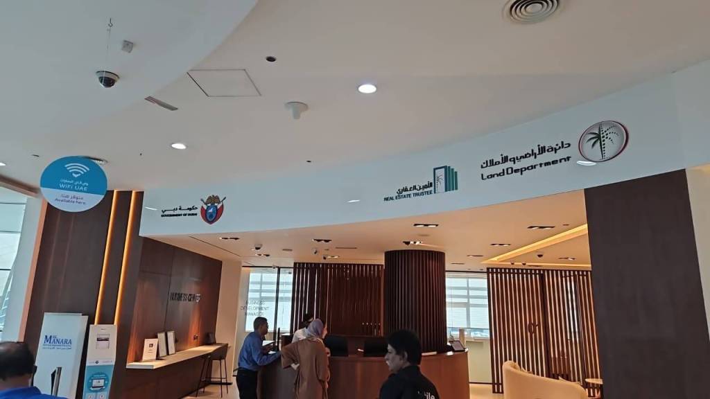Interior view of the Real Estate Registration Trustee LLC office at Al Manara Centre, Dubai, featuring a reception area with wooden paneling and signage.