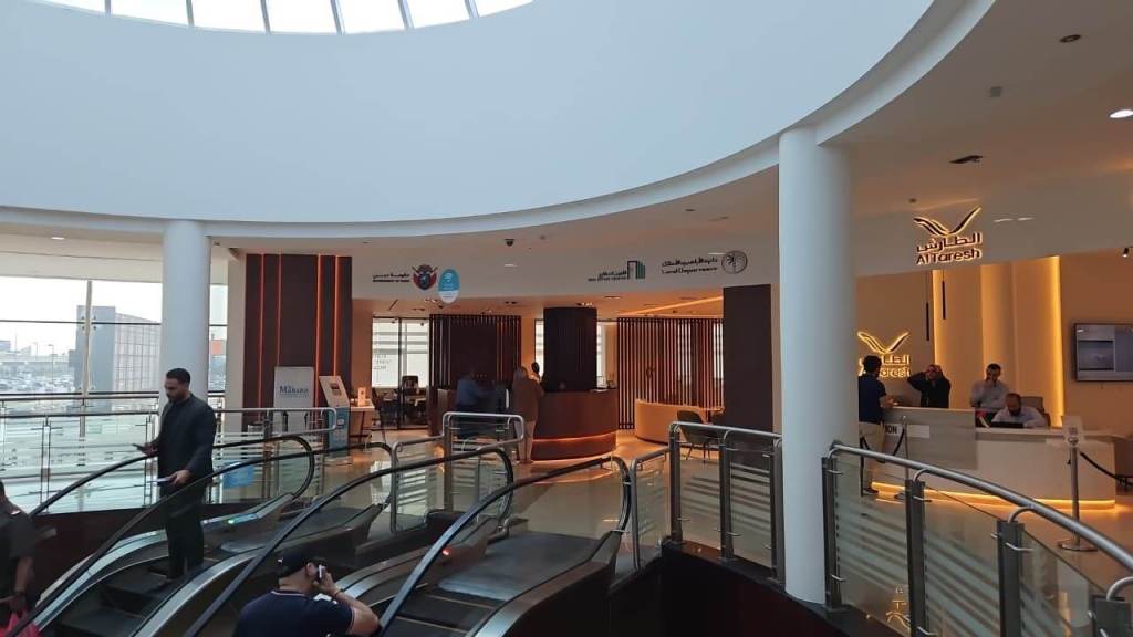 Interior view of the Real Estate Registration Trustee LLC office at Al Manara Centre in Dubai, showcasing an open design with visitors navigating the space and a reception area in the background.