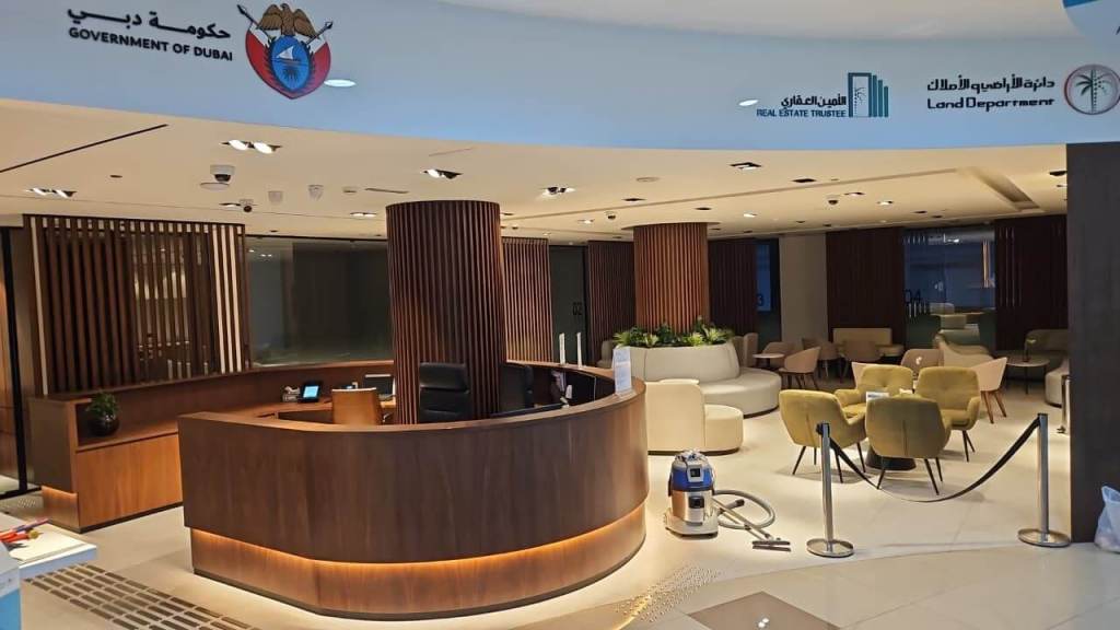Interior view of the Real Estate Registration Trustee LLC office in Al Manara Centre, Dubai, featuring a reception desk and seating area with modern decor.