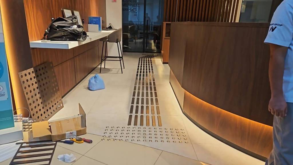 Interior view of the Real Estate Registration Trustee LLC office in Al Manara Centre, showing the installation of stainless steel tactile studs and lines on the floor for accessibility.
