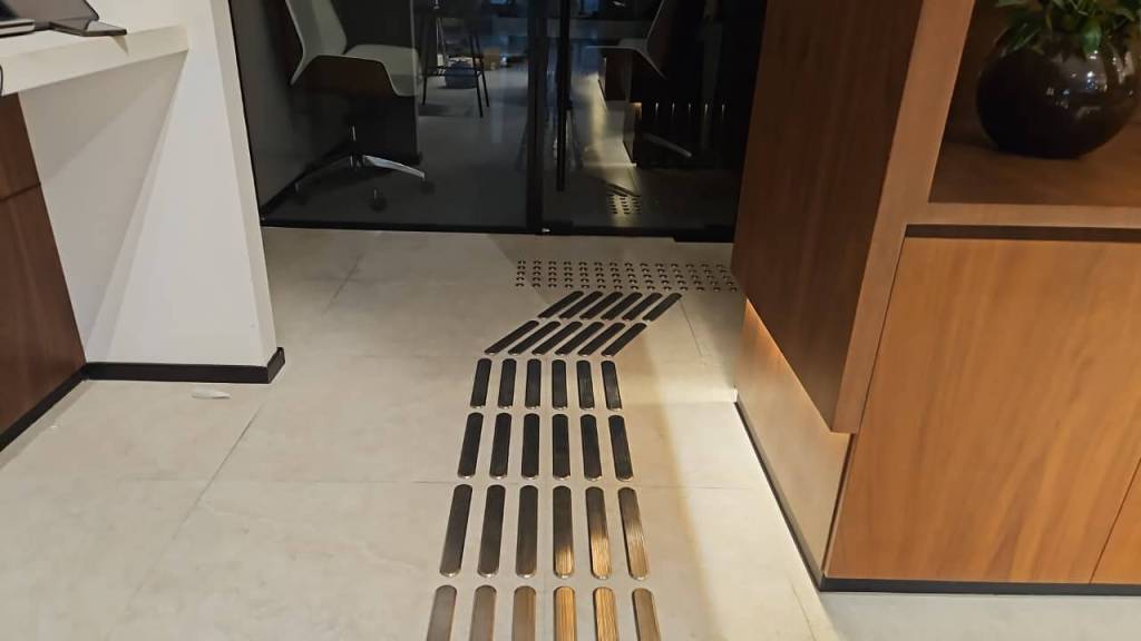 Interior view of the Real Estate Registration Trustee LLC office in Al Manara Centre, Dubai, featuring stainless steel tactile studs and lines installed on the floor for accessibility.