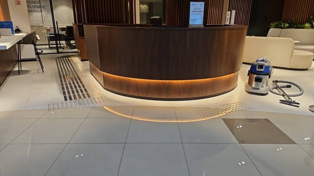 Interior view of the Real Estate Registration Trustee LLC office at Al Manara Centre, Dubai, showcasing a reception area with stainless steel tactile studs and lines installed for accessibility.