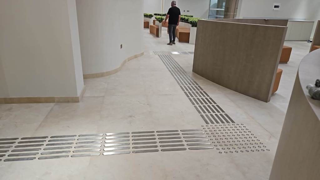 Interior view of Dubai Court at Manara Mall featuring tactile stainless steel self-adhesive strips and studs on the floor, providing guidance for visually impaired individuals.