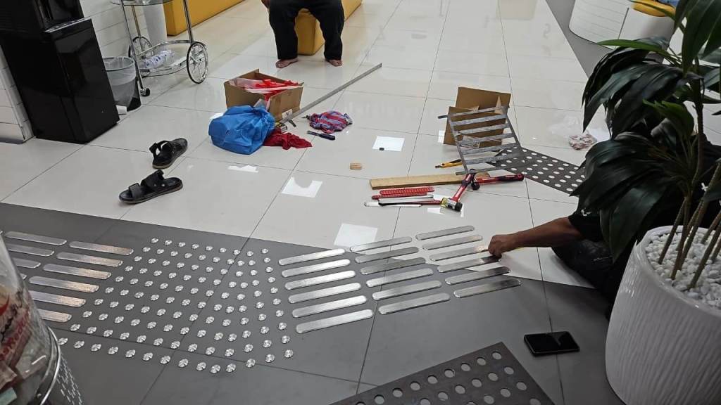 Installation of stainless steel tactile studs on the floor at On Time Business Solution L.L.C in Dubai, with tools and materials visible around.