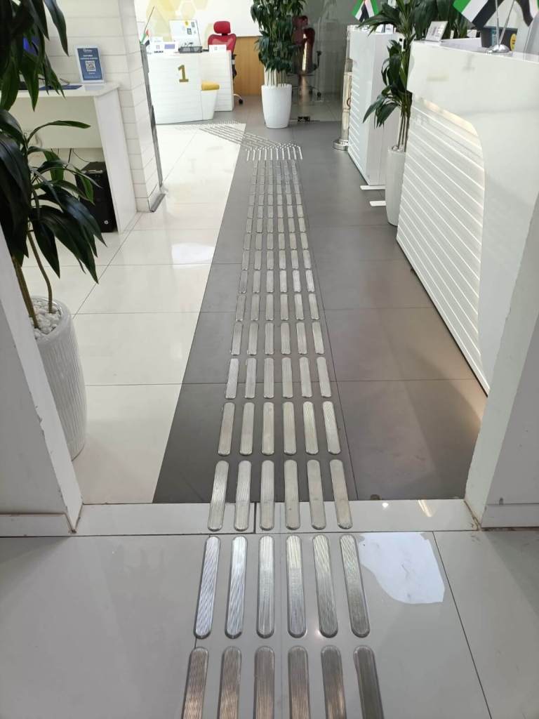 Interior view of On Time Business Solution office in Dubai, featuring stainless steel tactile studs and lines installed on the floor for improved accessibility.