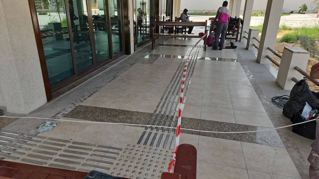 Workers installing stainless steel tactile indicators on the flooring at Majlis Al Bahar, Jumeirah, enhancing accessibility for visually impaired individuals.