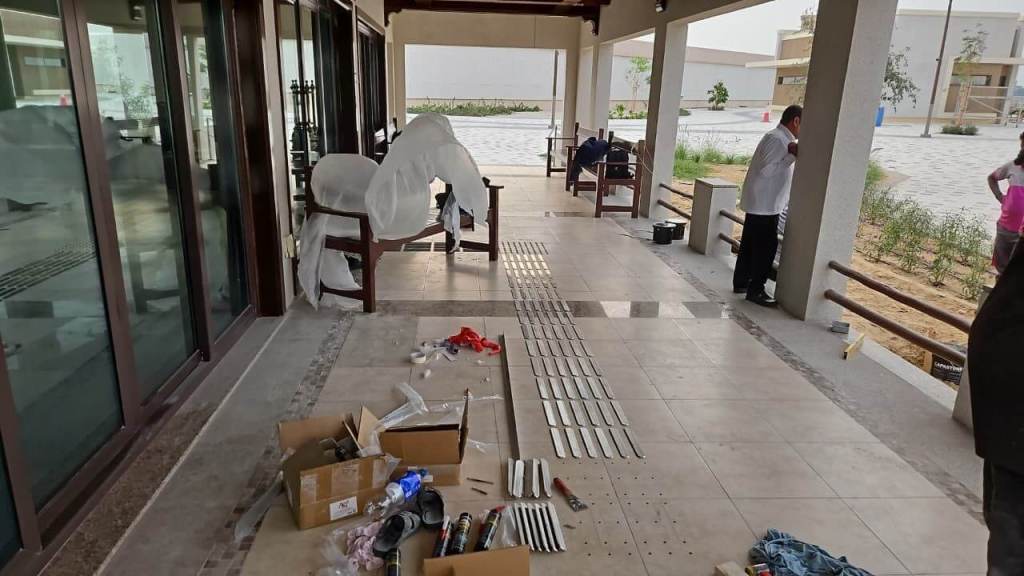Installation of stainless steel tactile pin-type studs on the floor at Prime FM, Majlis Al Bahar, Jumeirah, with construction materials and tools visible.