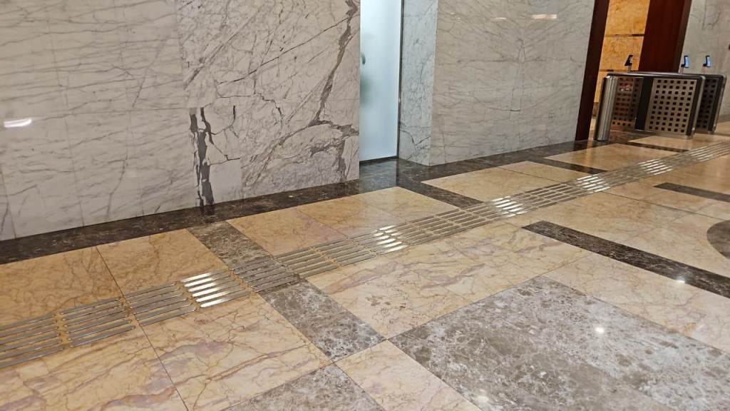 Interior hallway with marble flooring featuring a linear drain and a door in the background.