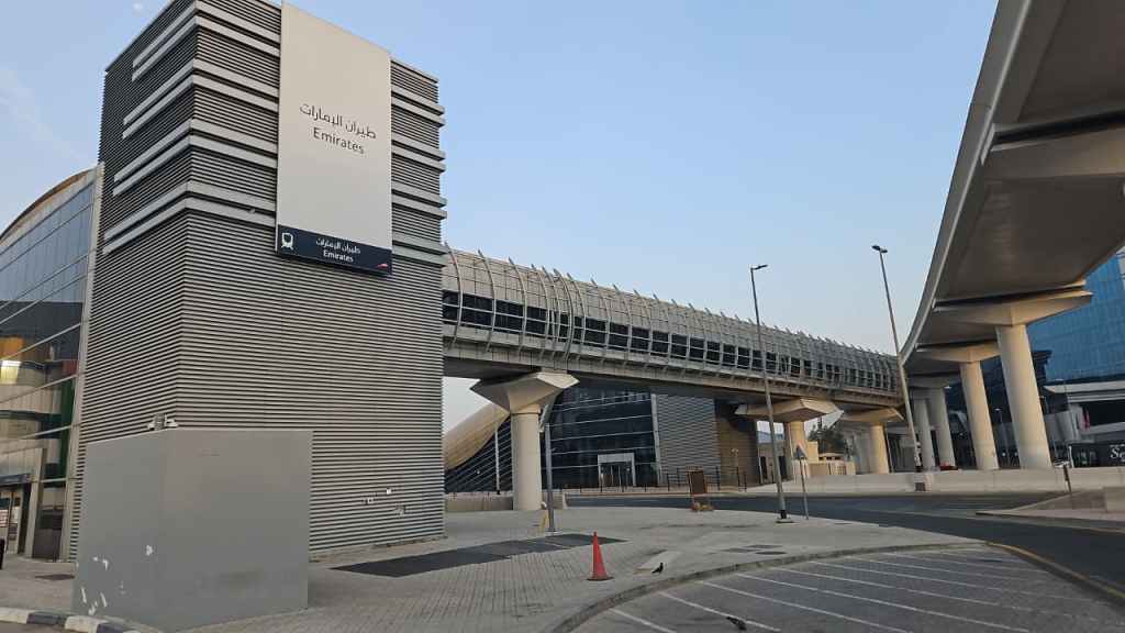 Exterior view of the Emirates terminal building at an airport, featuring modern architecture and signage in Arabic and English.