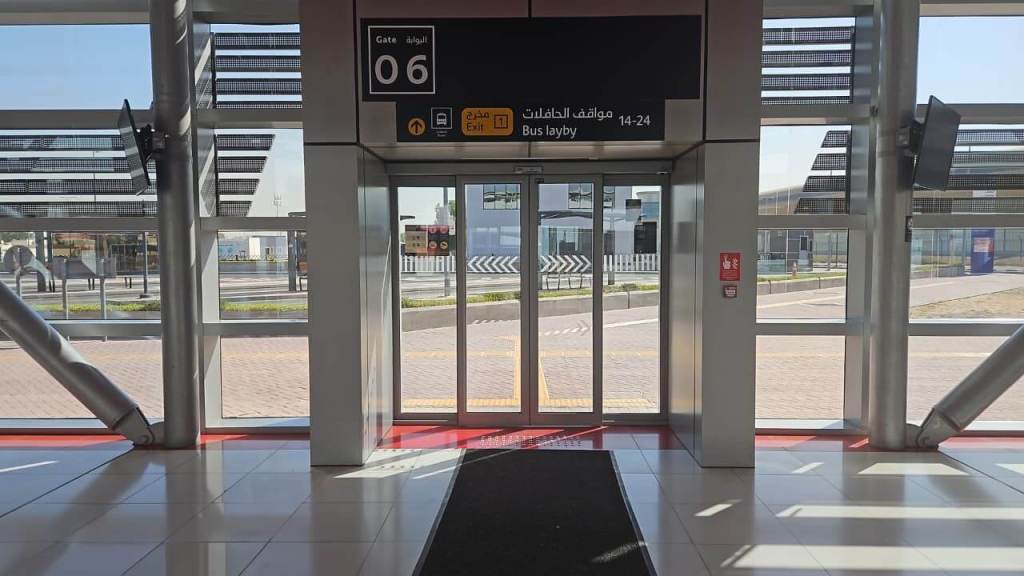 Interior view of an airport gate area with signage for Gate 06, indicating an exit and bus layby.