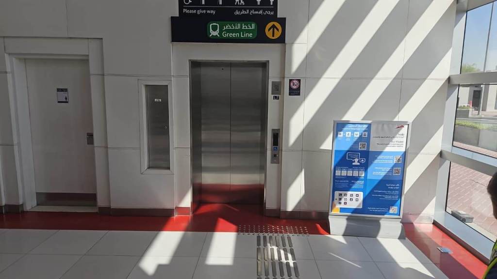 Elevator and sign indicating the Green Line direction in a public space, with informational poster beside it.