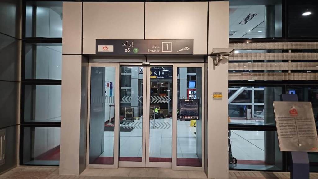 Entrance to a modern transportation hub labeled 'Entrance 1' with visible automated doors and signage in Arabic and English.