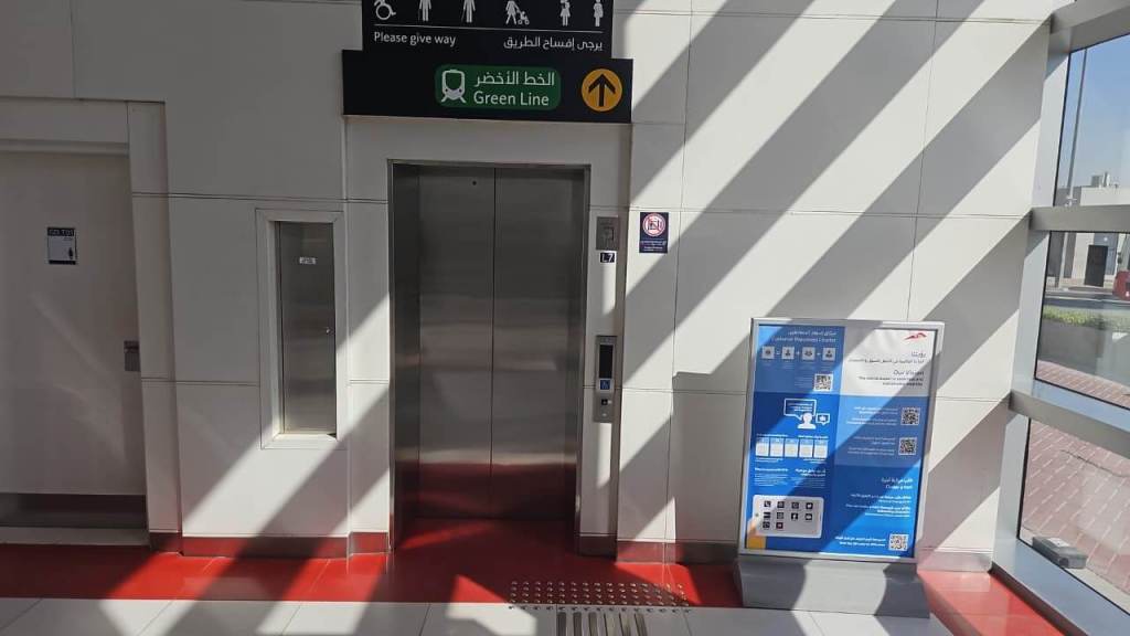 Elevator entrance with a sign indicating the Green Line and directional arrows, alongside a digital information board
